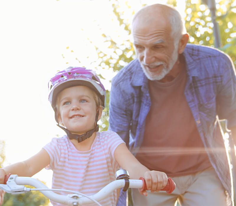 Grandfather teaching granddaughter how to ride a bike